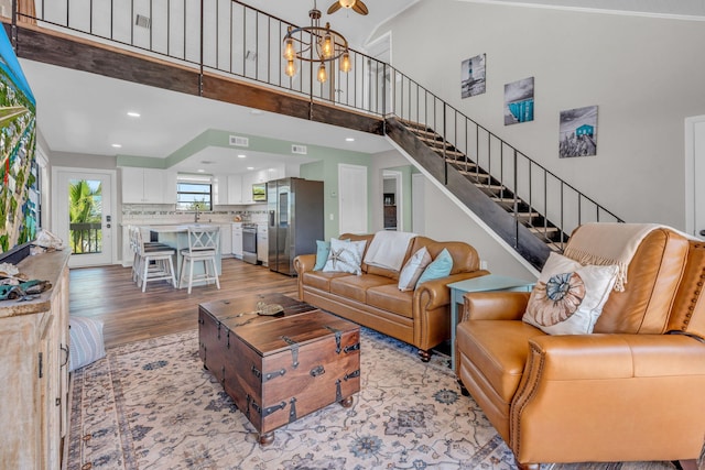 living room featuring an inviting chandelier, sink, a high ceiling, and light wood-type flooring