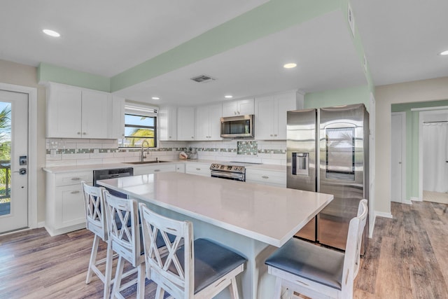 kitchen featuring appliances with stainless steel finishes, sink, a breakfast bar area, and white cabinets