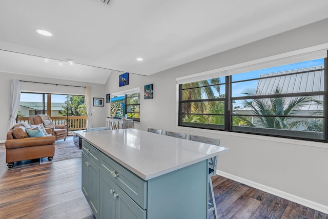 kitchen with vaulted ceiling, a kitchen island, dark hardwood / wood-style floors, and a breakfast bar area