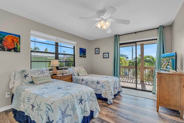 bedroom featuring dark hardwood / wood-style flooring, access to exterior, multiple windows, and ceiling fan