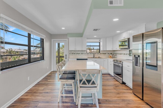 kitchen featuring white cabinetry, a kitchen island, a breakfast bar, and appliances with stainless steel finishes