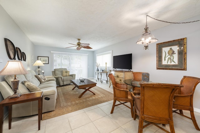 tiled living room with ceiling fan with notable chandelier and a textured ceiling