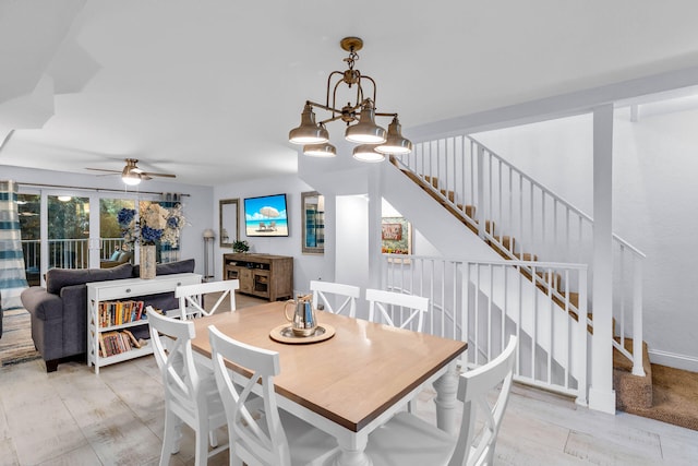 dining room with ceiling fan with notable chandelier and stairway