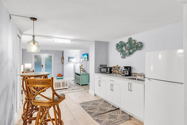 97501 Overseas Hwy Unit 705, Key Largo, FL 33037 - kitchen featuring freestanding refrigerator, light countertops, french doors, white cabinetry, and a sink