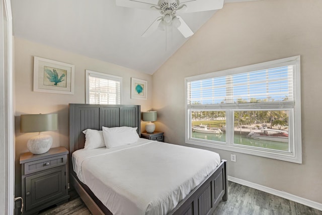 bedroom with vaulted ceiling, a water view, dark wood-type flooring, and ceiling fan