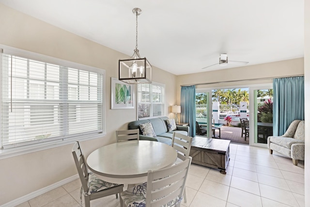 tiled dining room with ceiling fan with notable chandelier