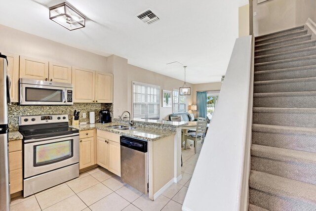 kitchen with sink, light tile patterned floors, kitchen peninsula, stainless steel appliances, and backsplash