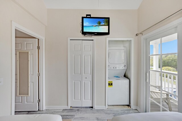 washroom with light hardwood / wood-style flooring and stacked washing maching and dryer