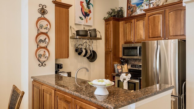 101 Front St Unit 8, Key West, FL 33040 - kitchen with appliances with stainless steel finishes, brown cabinetry, dark stone counters, and a peninsula
