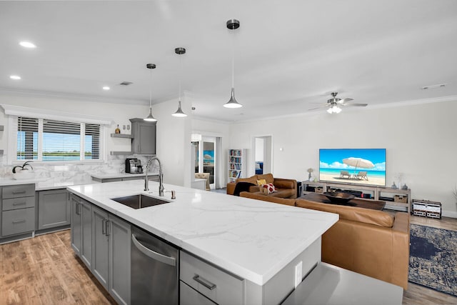 kitchen featuring gray cabinetry, light stone countertops, pendant lighting, sink, and a kitchen island with sink