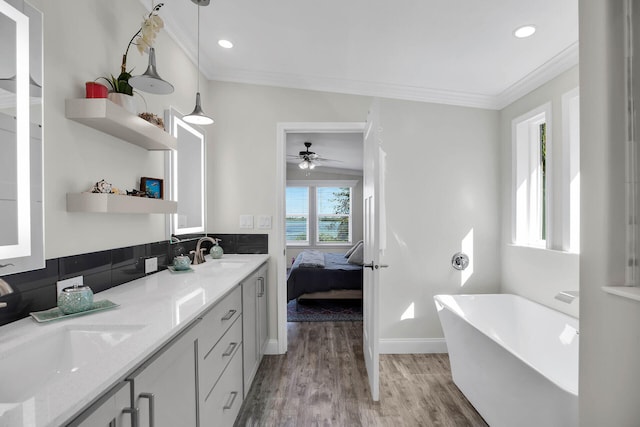 bathroom with ornamental molding, vanity, wood-type flooring, and a bath