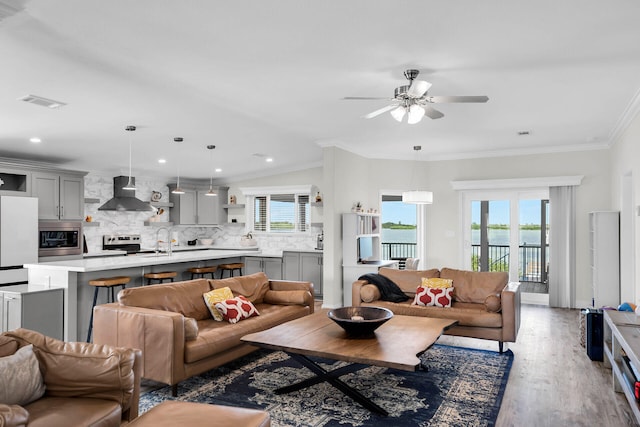 living room featuring wood-type flooring, crown molding, sink, and ceiling fan