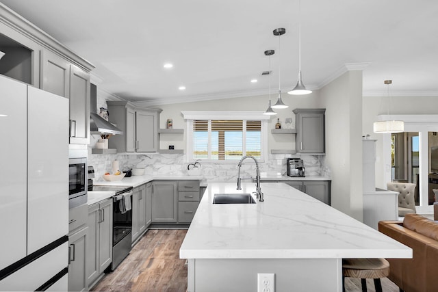 kitchen featuring appliances with stainless steel finishes, sink, a kitchen island with sink, and decorative light fixtures