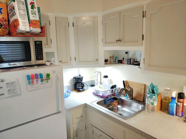 kitchen featuring white cabinetry, sink, and white fridge