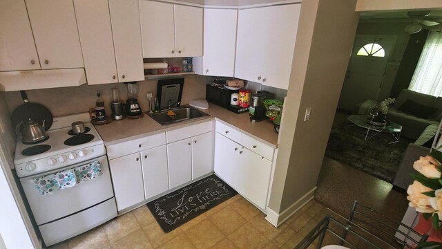 kitchen with electric stove, white cabinetry, and sink