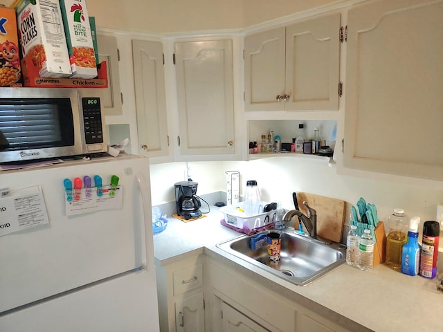 kitchen featuring white refrigerator, white cabinetry, and sink