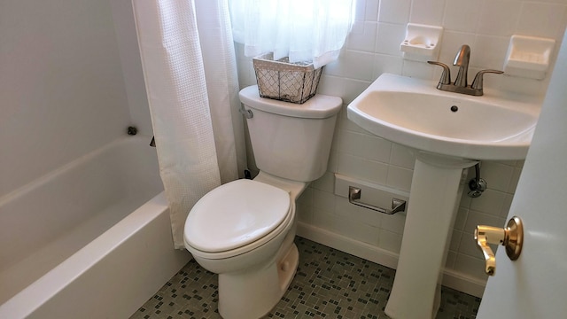 full bathroom featuring tile patterned floors, toilet, tile walls, shower / bath combo with shower curtain, and decorative backsplash