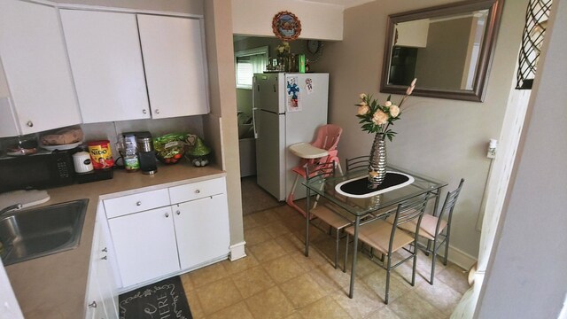 kitchen with white cabinetry, sink, and white refrigerator