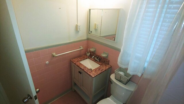 bathroom featuring vanity, tile walls, and toilet