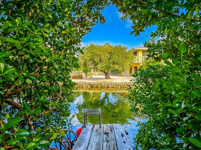 view of dock with a balcony and a water view