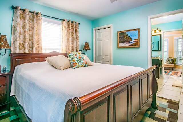 tiled bedroom featuring multiple windows, ensuite bath, and a closet