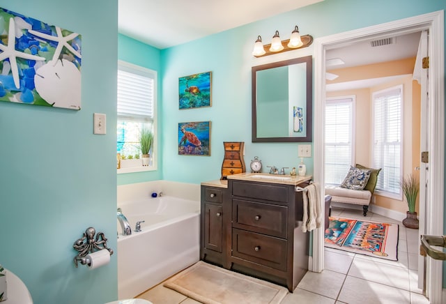 bathroom featuring vanity, a bathtub, tile patterned floors, and a healthy amount of sunlight