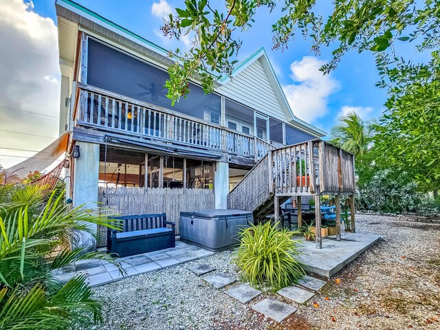 rear view of house with a wooden deck, a hot tub, and a patio area