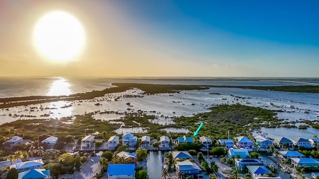 aerial view at dusk featuring a water view and a beach view