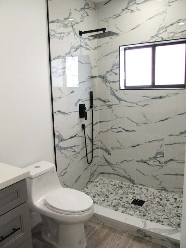 bathroom featuring vanity, tiled shower, and toilet