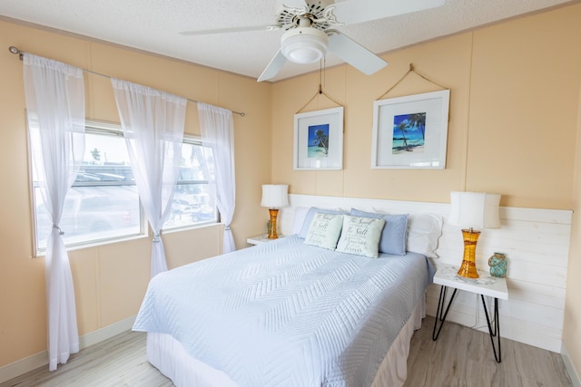 bedroom with ceiling fan, light hardwood / wood-style flooring, and a textured ceiling