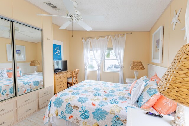 bedroom with ceiling fan, a textured ceiling, and light hardwood / wood-style floors