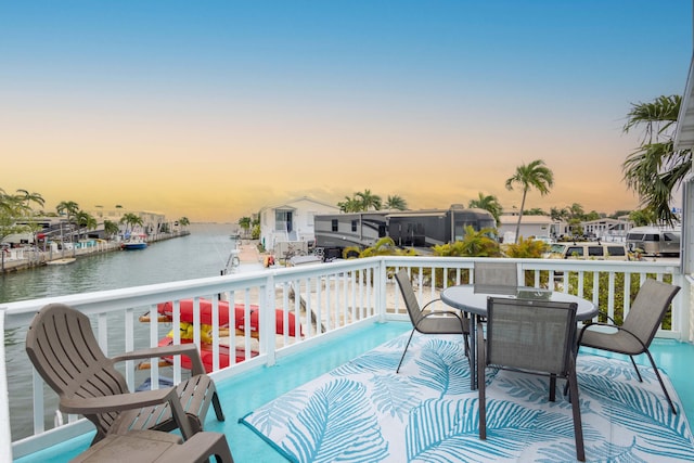 balcony at dusk featuring a water view