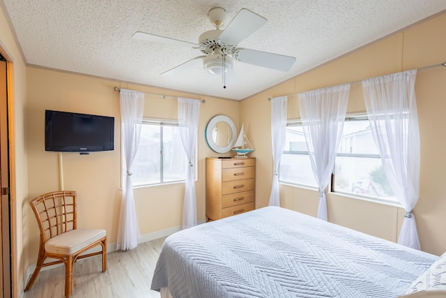 bedroom with hardwood / wood-style floors, vaulted ceiling, a textured ceiling, and ceiling fan