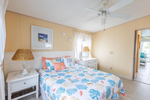 bedroom with ceiling fan, a textured ceiling, and light hardwood / wood-style floors