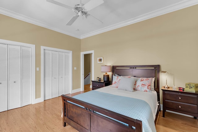 bedroom featuring light wood-type flooring, multiple closets, baseboards, and crown molding