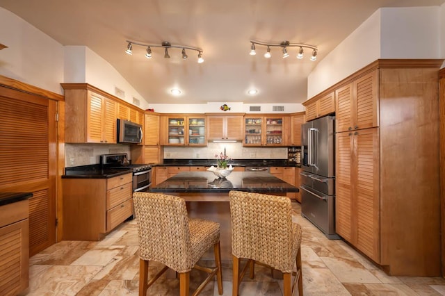 kitchen with stainless steel appliances, a center island, vaulted ceiling, and decorative backsplash