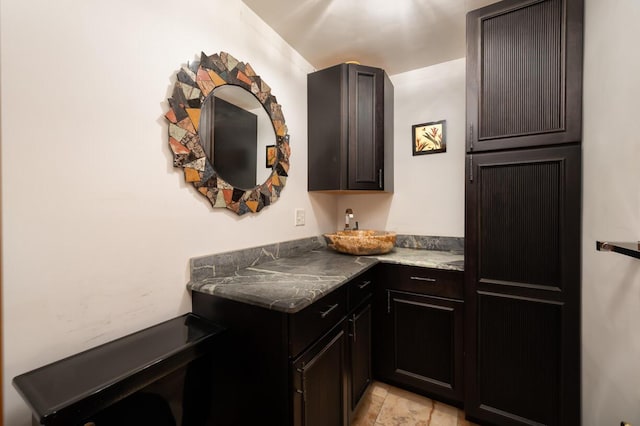 kitchen featuring dark brown cabinets and dark stone counters