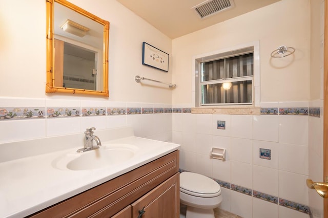 bathroom featuring vanity, tile walls, and toilet