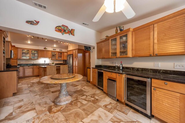 kitchen with wine cooler, ceiling fan, stainless steel appliances, and dark stone countertops