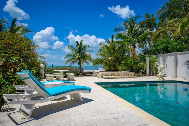 view of swimming pool featuring a patio and a water view