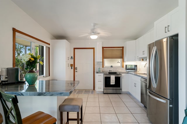 kitchen with light tile patterned floors, stainless steel appliances, a breakfast bar, and white cabinets