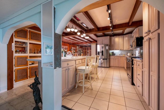 kitchen featuring a breakfast bar, beam ceiling, stainless steel appliances, track lighting, and light tile patterned flooring