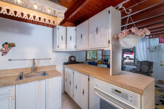 kitchen with wood ceiling, beamed ceiling, sink, and white cabinets