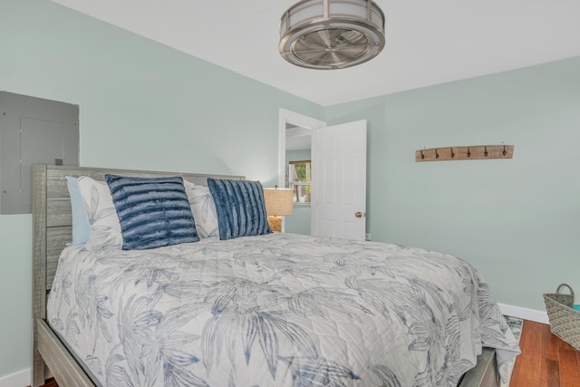 bedroom with wood finished floors, electric panel, and baseboards