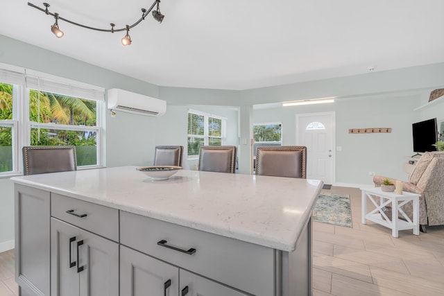 kitchen featuring a kitchen island, light stone counters, open floor plan, a healthy amount of sunlight, and a wall mounted AC