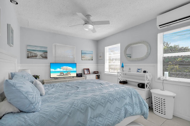 tiled bedroom featuring ceiling fan, a textured ceiling, and a wall unit AC