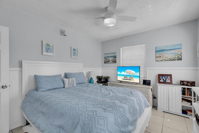 bedroom featuring ceiling fan, a textured ceiling, and light tile patterned floors