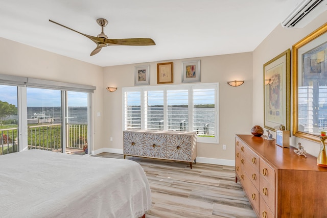 bedroom with access to outside, multiple windows, light wood-style flooring, and a wall mounted AC