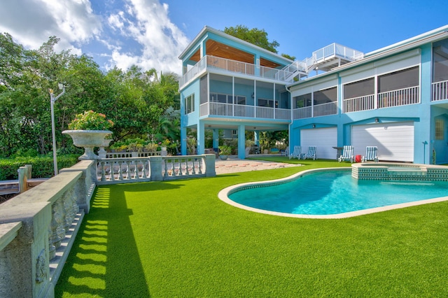 rear view of property with a patio, a lawn, and a pool with connected hot tub