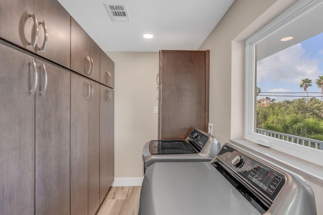 washroom with visible vents, baseboards, light wood-type flooring, independent washer and dryer, and cabinet space